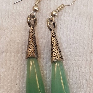 Pu&ograve; includere: Un paio di orecchini pendenti in argento con pietre verdi a forma di lacrima.