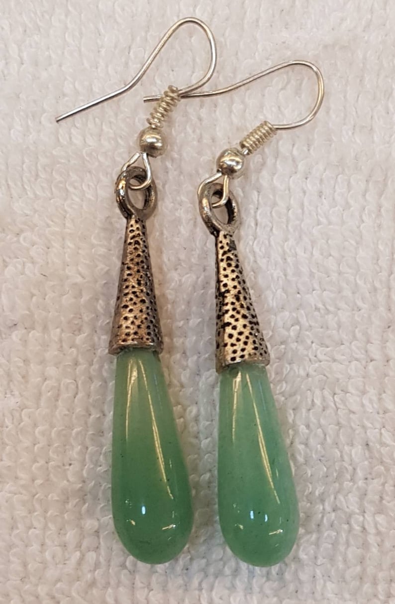 Pu&ograve; includere: Un paio di orecchini pendenti in argento con pietre verdi a forma di lacrima.
