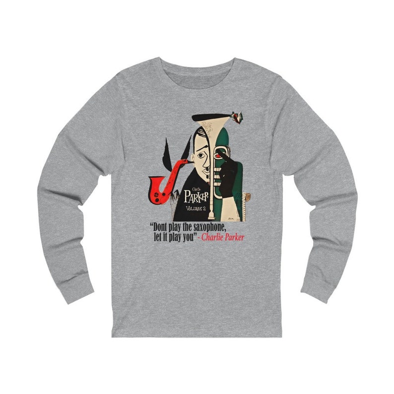 May include: A long-sleeve gray shirt featuring a stylized illustration of a saxophone player. The artwork includes a red saxophone, and the text "Charlie Parker Volume 2" and a quote by Charlie Parker.