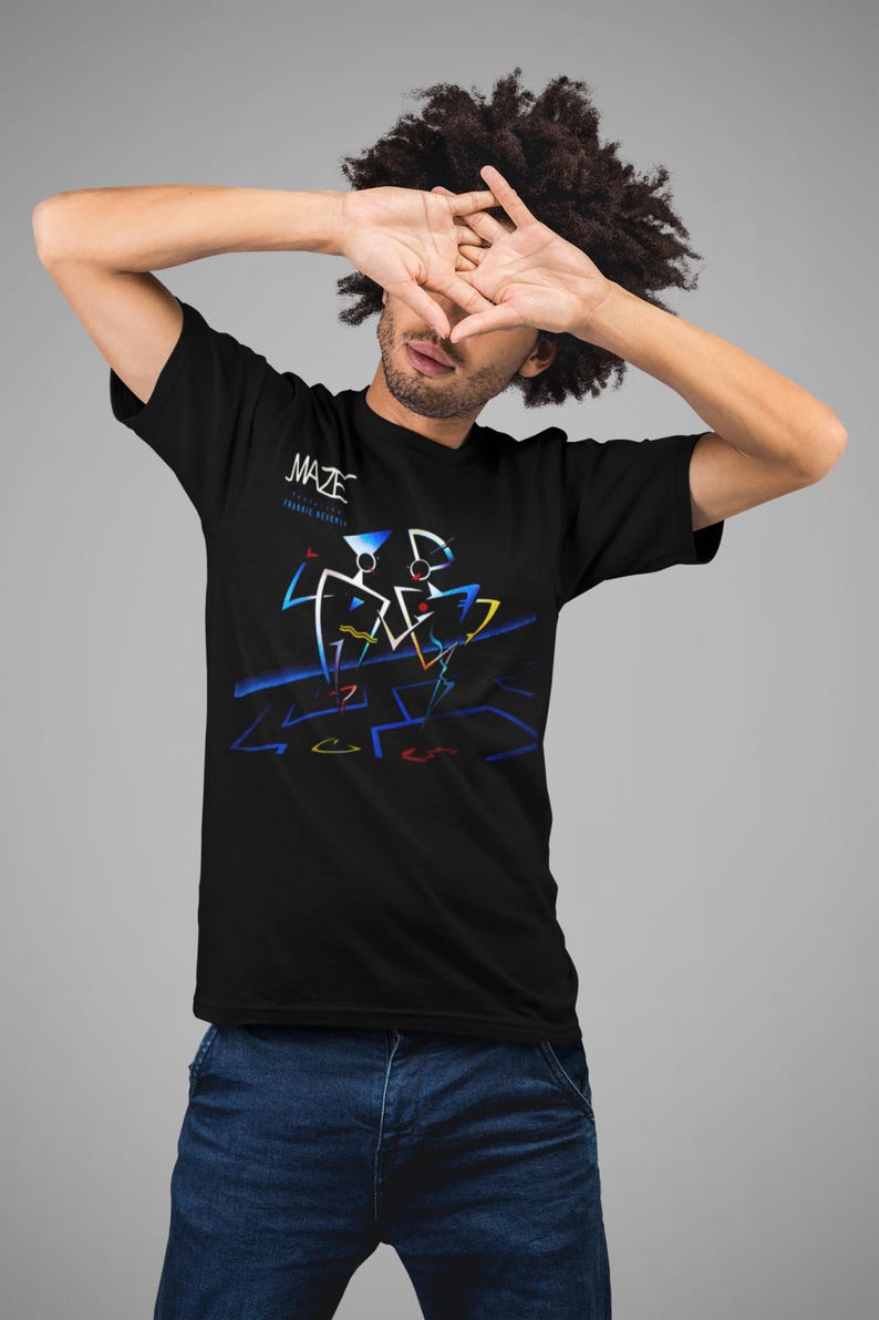 K&ouml;nnte beinhalten: Schwarzes T-Shirt mit dem Wort "MAZE" in wei&szlig;er Schrift &uuml;ber einem farbenfrohen geometrischen Design. Das Design zeigt blaue, gelbe und rote Linien und Formen. Das Shirt hat einen klassischen Rundhalsausschnitt.