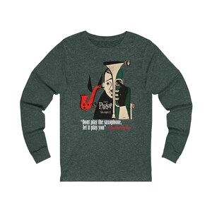 May include: Dark green long-sleeve shirt featuring a stylized illustration of Charlie Parker with a saxophone. The design includes the text "Charlie Parker Volume 2" and a quote: "Don't play the saxophone, let it play you."