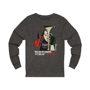 May include: Dark gray long-sleeve shirt featuring a jazz-themed graphic. The design includes a stylized illustration of a saxophone and a portrait of Charlie Parker, with the quote "Don't play the saxophone, let it play you."