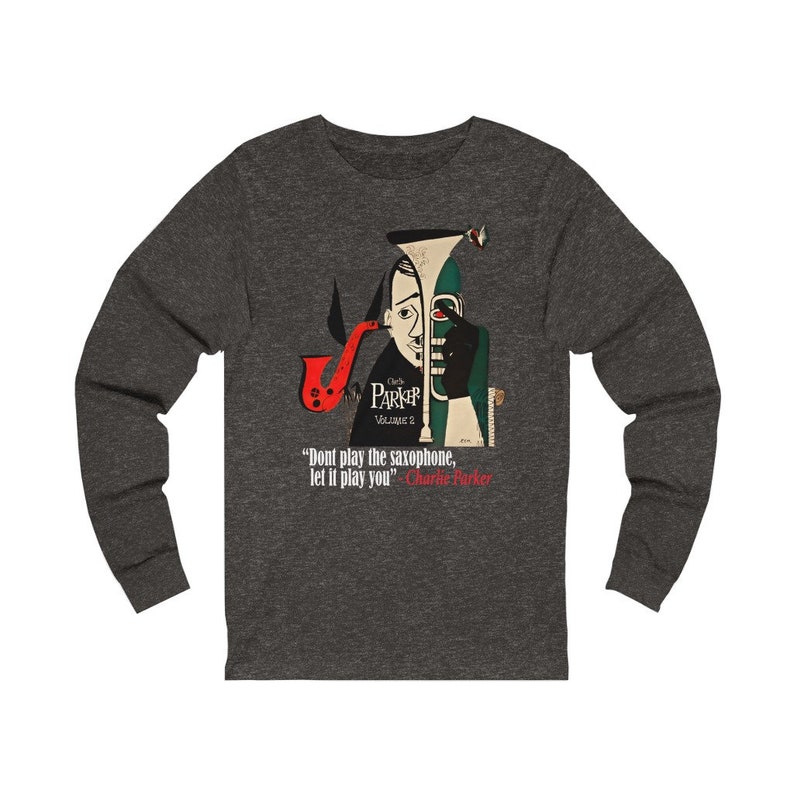 May include: Dark gray long-sleeve shirt featuring a jazz-themed graphic. The design includes a stylized illustration of a saxophone and a portrait of Charlie Parker, with the quote "Don't play the saxophone, let it play you."