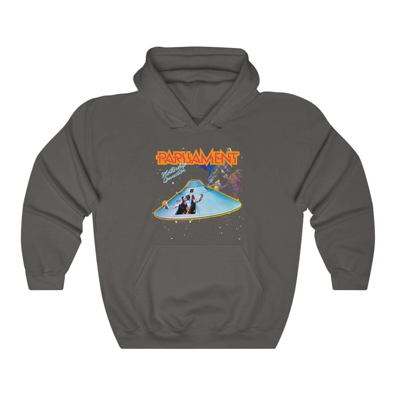 K&ouml;nnte beinhalten: Ein dunkelgrauer Kapuzenpullover mit einem Grafikdruck des Albumcovers von Parliaments "Mothership Connection". Das Albumcover zeigt eine fliegende Untertasse mit zwei Figuren darin, und der Bandname ist in orangefarbenen Buchstaben gedruckt.