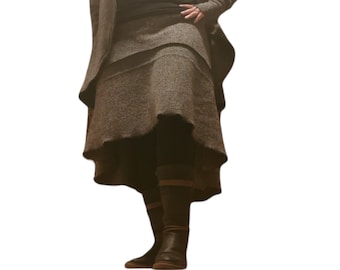 May include: A brown, long, layered skirt with a ruffled hem. The skirt is made of a textured fabric and is worn with black tights and brown boots.