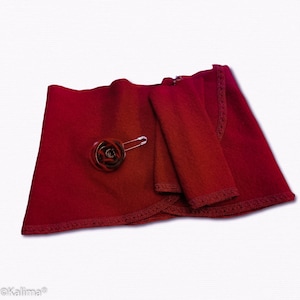 May include: A burgundy red wrap with a decorative rose brooch and a matching burgundy red fabric rectangle. The wrap has a scalloped edge.