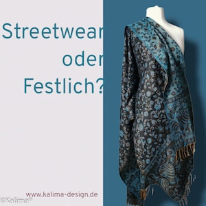 May include: A blue and black patterned shawl with gold accents. The shawl is draped over a mannequin against a blue background. The text "Streetwear oder Festlich?" is visible in the image.