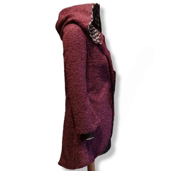 Jacke im Gehrock Stil aus feinen Boucle' Strick. Mit Kapuze und seitlichen Taschen aus handbedruckter Baumwolle