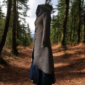 May include: A long, gray hooded coat with a long, flowing skirt. The coat is made of a soft, textured fabric and has a simple, elegant design.