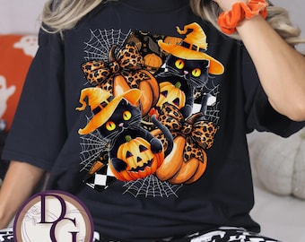 Puede incluir: Camiseta negra con un diseño de Halloween. Presenta gatos negros con sombreros de bruja, calabazas y lazos con estampado de leopardo. El diseño también incluye telarañas y un patrón de cuadros, ideal para Halloween.
