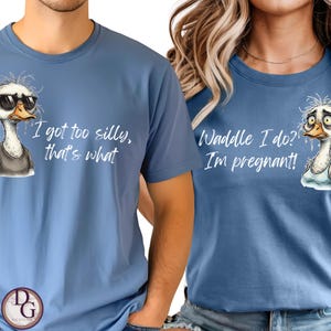 以下が含まれることがあります： アヒルのグラフィックとテキストが入った2枚の青いTシャツ。1枚は「I got too silly, that's what」、もう1枚は「Waddle I do? I'm pregnant!」と書かれています。アヒルのイラストはサングラスをしていて、困った顔をしています。