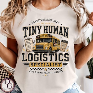 Può includere: Una t-shirt color crema con la grafica di uno scuolabus giallo, una cartellina con una lista di controllo e una tazza di caffè. Il testo recita: TRANSPORTATION DEPT. EST. 2026 TINY HUMAN LOGISTICS SPECIALIST FUELED BY CAFFEINE & DEDICATION.