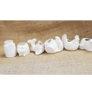 May include: A set of seven white ceramic planters, each shaped like a different animal, including a whale, a pig, a chicken, and a turtle. The planters are all unpainted and ready to be decorated.