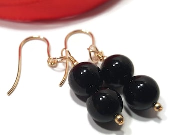 May include: Gold dangle earrings with two black round beads on each earring.