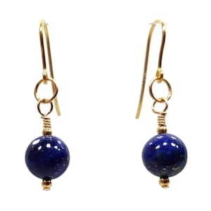 May include: A pair of gold earrings with a round, dark blue lapis lazuli gemstone on each earring.