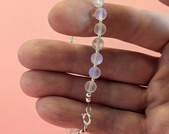 May include: A white iridescent beaded bracelet with a silver clasp.