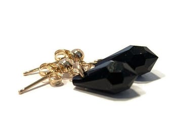 May include: A pair of gold earrings with black teardrop-shaped crystal accents.