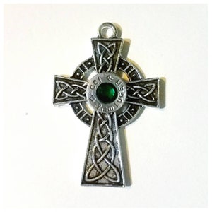 May include: A silver Celtic cross pendant with a 9mm Luger bullet casing in the center. The bullet casing has a green gemstone set in it.