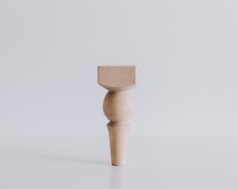 May include: A wooden furniture leg with a rounded ball shape and a square top.