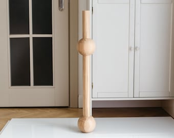 May include: A tall, wooden vase with a cylindrical body and two large, round spheres at the top and bottom. The vase is light brown in colour and has a natural wood grain.