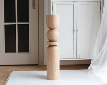 Puede incluir: Una escultura de madera con una base cilíndrica y tres esferas apiladas. La escultura está hecha de madera marrón claro y tiene un acabado liso y pulido.