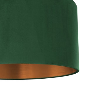 Puede incluir: Una pantalla de l&aacute;mpara de terciopelo verde con fondo de cobre.