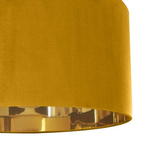 May include: A mustard yellow velvet lampshade with a gold trim around the bottom edge.