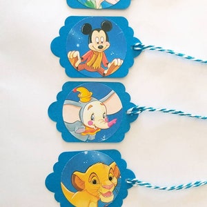 May include: Five blue gift tags with scalloped edges and white twine. Each tag features a different Disney character: Ariel, Mickey Mouse, Dumbo, Simba, and Snow White.