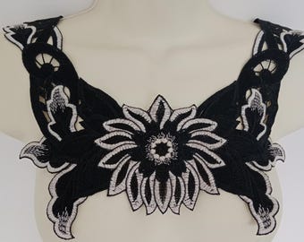 May include: Black and white floral lace trim with a large flower in the center. The lace is delicate and intricate, with a scalloped edge.