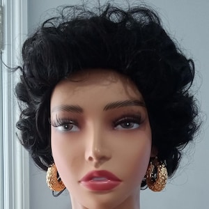 Op de afbeelding: Een mannequin met kort, krullend zwart haar draagt grote gouden oorringen. De oorringen hebben een getextureerd ontwerp.