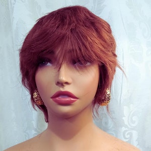 May include: A mannequin with short, auburn-colored hair wearing gold hoop earrings.