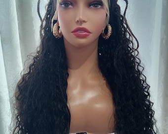 May include: A long, black, curly wig with braids woven into the hair. The wig is on a mannequin head with a light brown skin tone. The wig is styled with a middle parting and the braids are pulled back from the face.
