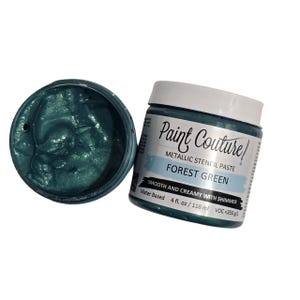 May include: Open jar of forest green metallic stencil paste next to a closed jar. The label reads "Paint Couture" and "FOREST GREEN". The paste is water based, smooth, creamy, and has shimmer. The jar contains 4 fl. oz. / 118 ml.