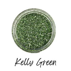 May include: A clear glass jar filled with Kelly Green glitter. The glitter is a vibrant green color with small, reflective particles. The words "Kelly Green" are written in a cursive font below the jar.