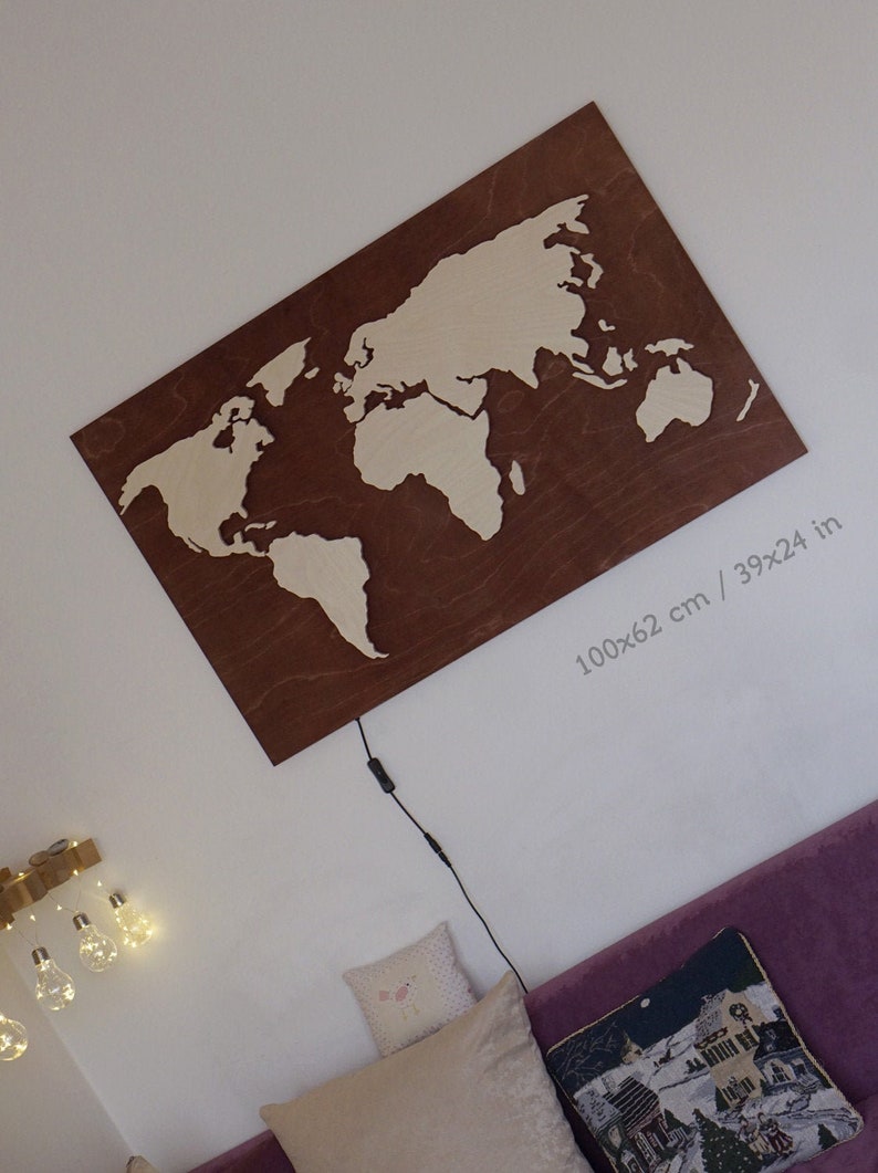 May include: A wooden world map cutout with a brown background and white continents. The map is 39x24 inches or 100x62 cm.