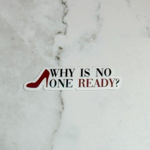 May include: A white sticker with the text "WHY IS NO ONE READY?" in black and red. A red high heel shoe graphic is incorporated into the design. The sticker is rectangular with a white border.