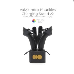 Può includere: Supporto di ricarica nero per Valve Index Knuckles v2 con logo dorato. Il supporto contiene due controller VR. Il testo sul supporto dice "Valve Index Knuckles Charging Stand v2".