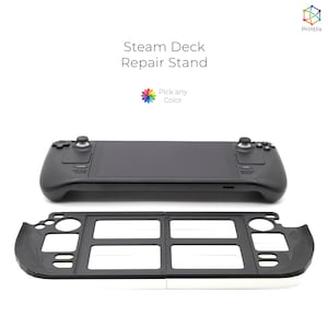 Könnte beinhalten: Ein schwarzer Steam Deck Reparaturständer mit weißem Innenraum. Der Ständer ist so konzipiert, dass er die Steam Deck während der Reparatur festhält. Der Ständer ist aus Kunststoff und hat ein schlichtes Design.