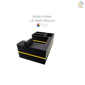 May include: Black wall mount organiser with yellow accents. It has compartments for storing items and a small shelf on the side. The text "Valve Index LX Wall Mount" is printed on the top of the organiser. The text "Pick any Colour" is printed below the main text.