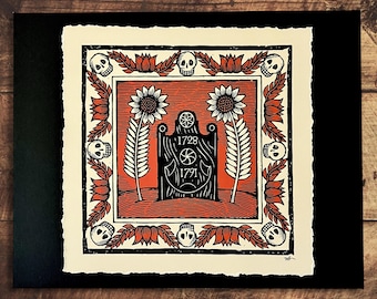 May include: A black and red linocut print featuring a central tombstone design with the dates 1728 and 1791. The print is framed by a border of skulls, flowers, and stylized leaves. The artwork is on textured paper.
