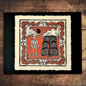 May include: A Halloween-themed art print featuring a skeleton standing in front of a stack of hay bales. The print has an orange and black color scheme, with a decorative border of pumpkins and flowers. A black cat and moon are in the sky.