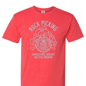 May include: Red heather t-shirt with a gray graphic of rocks and the text "Rock Picking" above a gray seal with the text "Stanhope State University College of Farming" and the text "Agricultural Geology Masters Program" below the seal.