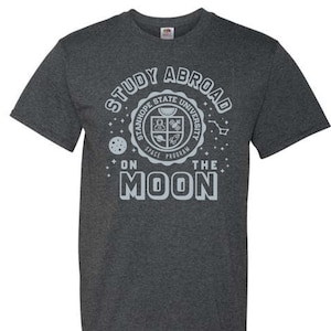 May include: Dark grey t-shirt with a white graphic that says "Study Abroad on the Moon" and features a logo for Stanhope State University's Space Program.