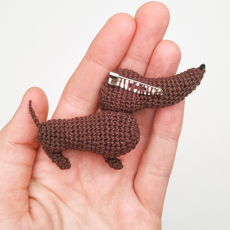 May include: A brown crocheted dachshund brooch with a silver safety pin.