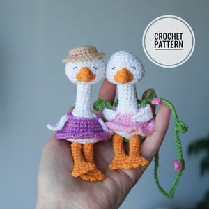 Peut inclure: Deux jouets amigurumi en forme d'oie en crochet portant des robes et des chapeaux. L'oie à gauche porte une robe violette et un chapeau de paille. L'oie à droite porte une robe rose. Le texte CROCHET PATTERN est visible sur l'image.