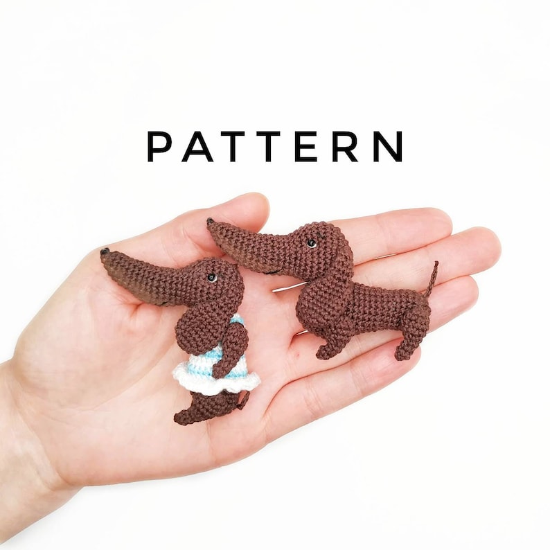 May include: Two crocheted dachshund dog toys. One is brown and the other is brown with a blue and white striped dress.