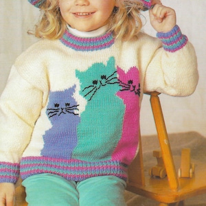 May include: Knitting pattern for a children's sweater with a cat design. The sweater is white with a pink, blue, and green striped band around the neck and cuffs. The cat design is in pink, blue, and green. The pattern is called "PDF Pattern".