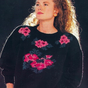 Op de afbeelding: Een zwarte trui met een bloemenpatroon in roze en blauw. De trui heeft een ronde hals en lange mouwen. De tekst "PDF Pattern" staat onderaan de afbeelding.