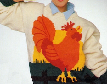 May include: Knitting pattern for a white sweater with a colorful rooster design. The sweater has a blue collar and a blue and green background with a black fence. The pattern is called "Io" and is a PDF download.