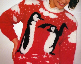 May include: A red knitted sweater with a white and black penguin design. The sweater has a white snowflake pattern and the text "Io" at the top. The text "PDF Pattern" is at the bottom of the image.